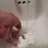 bath bomb fizzing in water leaving a white trail with some black from charcoal